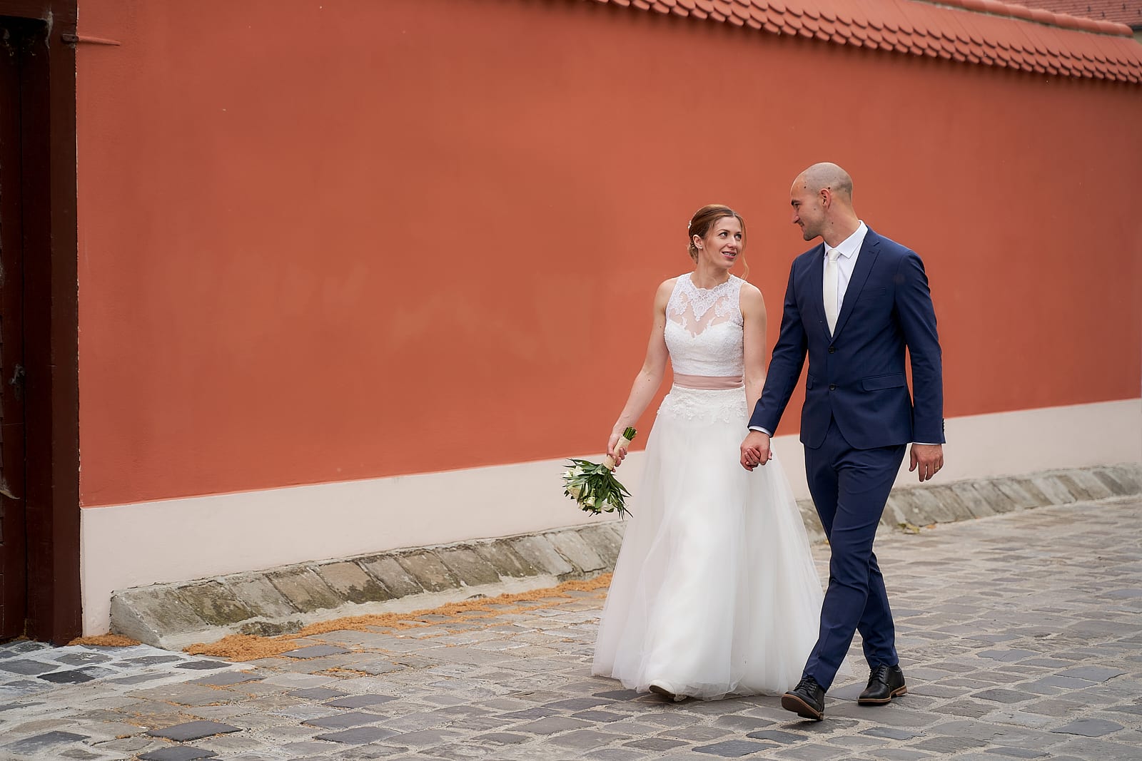 Győrben, egy narancssárga ház előtt sétáló házaspár